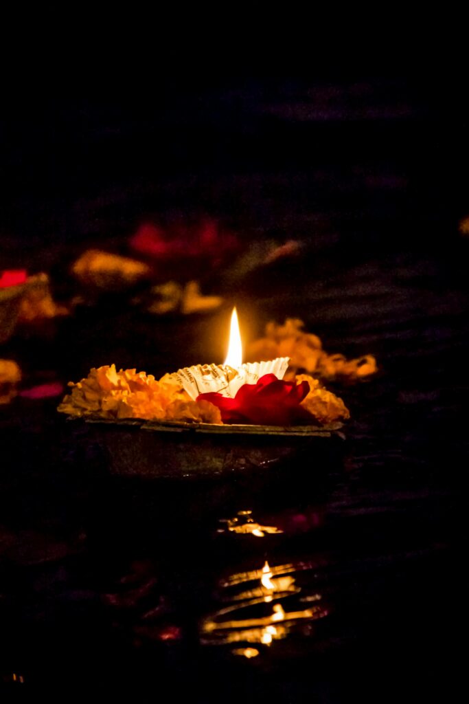 A close-up of a candle with flowers on water during a spiritual festival, creating a serene ambiance.